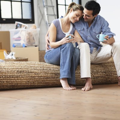 Couple embracing, sitting on mat indoors, smiling