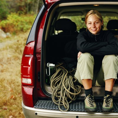 Femal rock climer sitting with gear in back of SUV, portrait