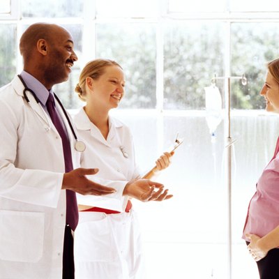 portrait of a young doctor and nurse talking to a pregnant woman
