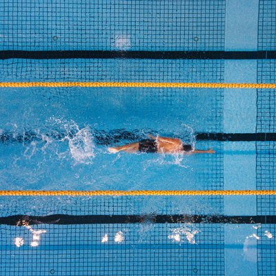 Top view shot of young man swimming laps in a swimming pool. Male swimmer swimming the front crawl in a pool.