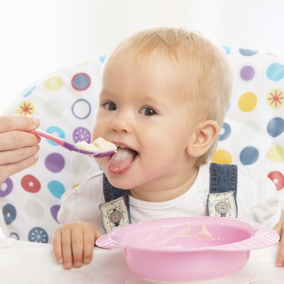 happy mother feeds funny baby from spoon