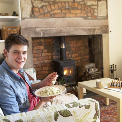 Young man eating meal by fire