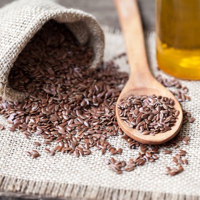 Flax seeds in the sack and oli on wooden background
