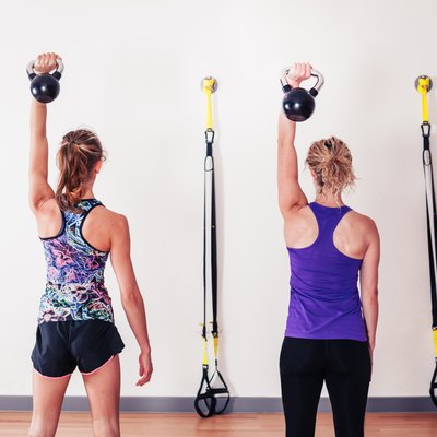 Women doing shoulder press with kettlebells