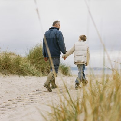 Father and Son Walk Over a Sand Dune Holding Hands