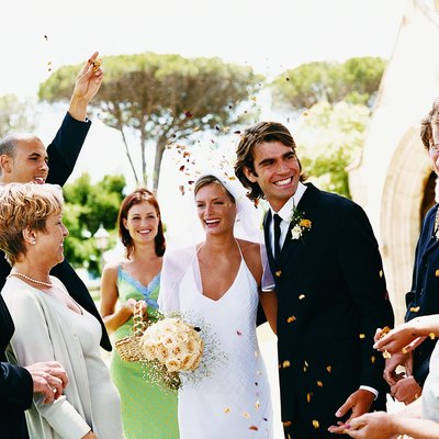 People Throwing Confetti Over a Newlywed Couple Leaving Church