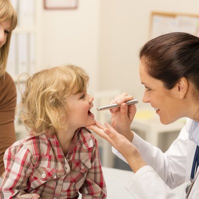 Pediatrician examine child throat look with light