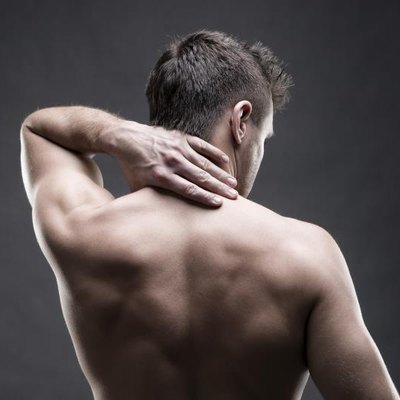 Pain in the neck. Man with backache. Muscular male body. Handsome bodybuilder posing on gray background. Low key close up studio shot. Middle part of the body