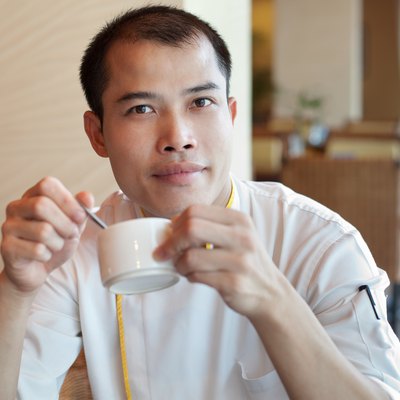 Chinese chef wearing uniform enjoying coffee break in restaurant cafe