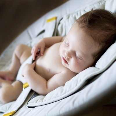 Newborn baby girl sleeping on bouncer chair in dark room