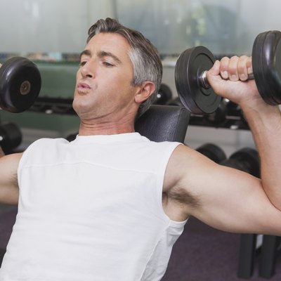 Fit man lifting dumbbells lying on the bench