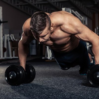 Handsome muscular man doing pushup exercise with dumbbell