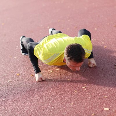 Man exercises outdoors with knuckle push-ups..