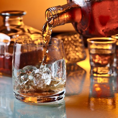 glass with whiskey and ice on a glass table