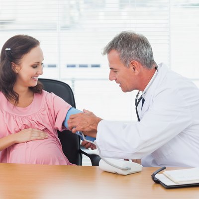 Doctor taking blood pressure of pregnant patient