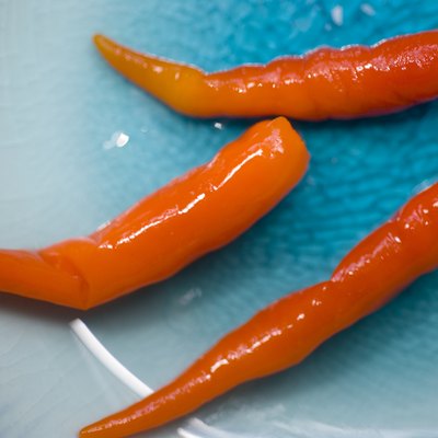 Close-up view of three red chilis on a blue plate.