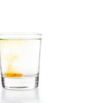 Effervescent vitamin C tablet bubbles in glass of water