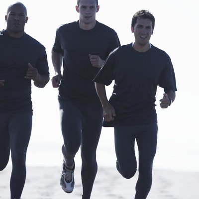 Four men jogging on beach