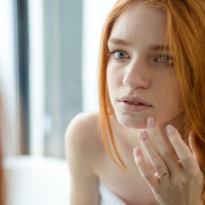 Redhead woman looking at her reflection in mirror