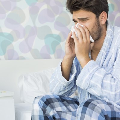 Sick man blowing his nose in tissue paper