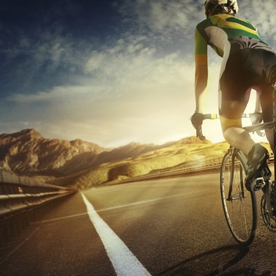 Cyclist riding a bike to the sunset on the highway