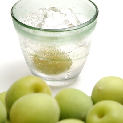 Unripe plums and glass of plum liquor.