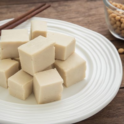 Tofu cubes on plate and soy beans in bowl