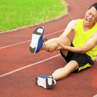young male runner suffering from leg cramp on the track