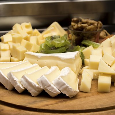 Assorted cheese on a wooden board under warm light