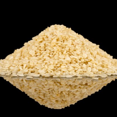 White sesame seeds on black reflective surface