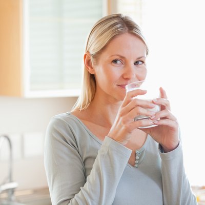 Woman standing in the kitchen drinking some water