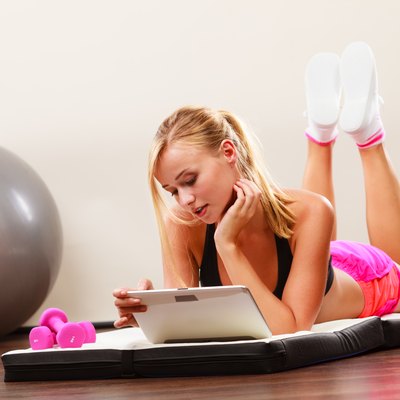 Fit woman lying on floor with tablet pc