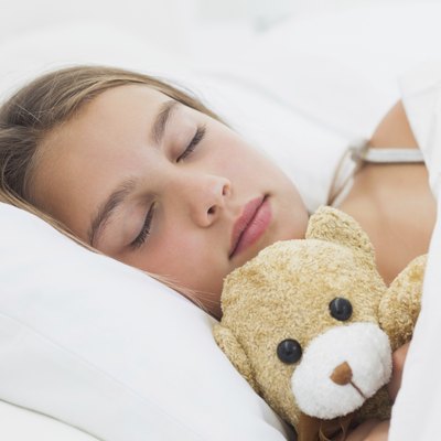 Cheerful girl sleeping with her teddy bear