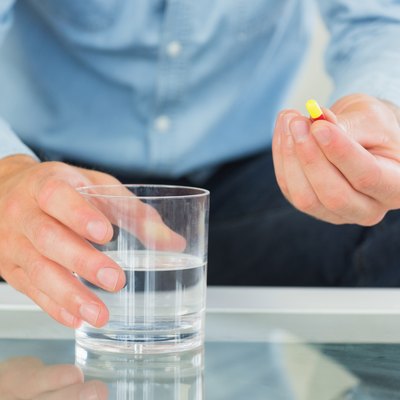 Close up of man holding glass of water and pill