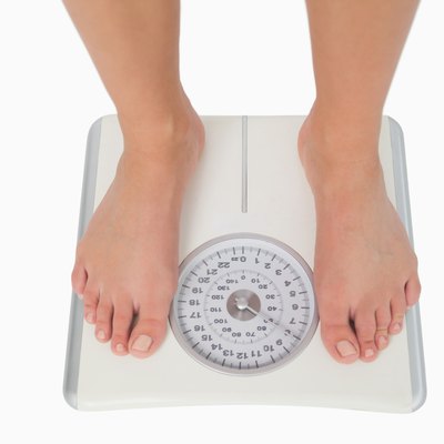 Female feet standing on a white scales