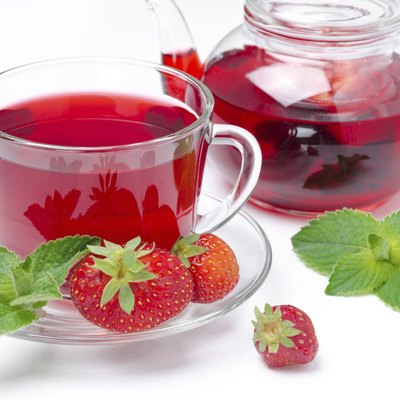 kettle and cup of red tea with strawberries, mint