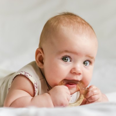 Baby girl on her stomach with teether in the mouth
