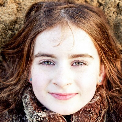 Head shot portrait of young girl lying back on beach