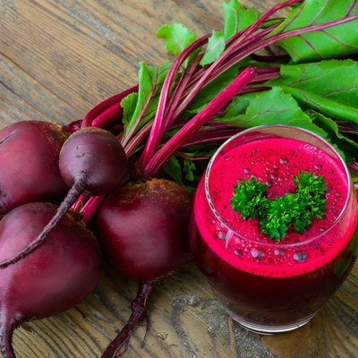 Glass of fresh beetroot juice with bets on wooden table