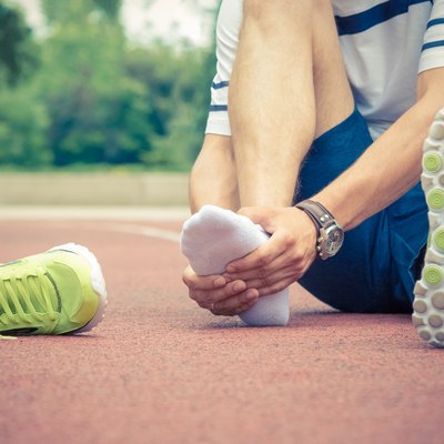 Jogger checking if his ankle is broken or twisted
