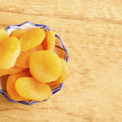 Bowl of dried apricots on wooden table background.
