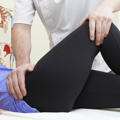 Male Osteopath Treating Female Patient With Hip Problem