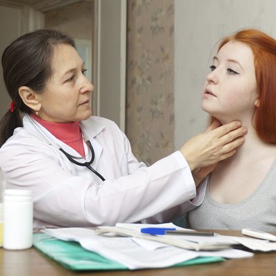 Mature doctor touching neck of teenager