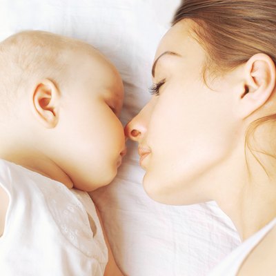 Baby and mother sleeping together on the bed