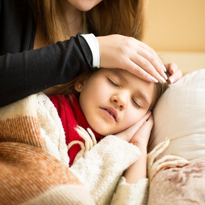 Closeup of caring mother holding head on sick daughter forehead