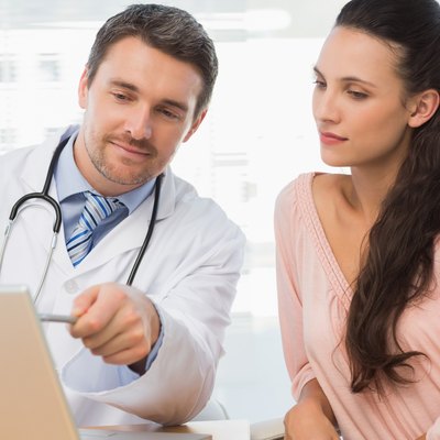 Male doctor showing something on laptop to patient