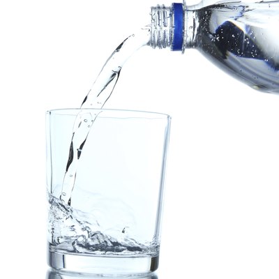 Pour water from bottle into glass, on light blue background