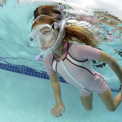 child swimming underwater in pool