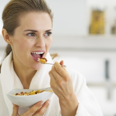 Young housewife having healthy breakfast in kitchen