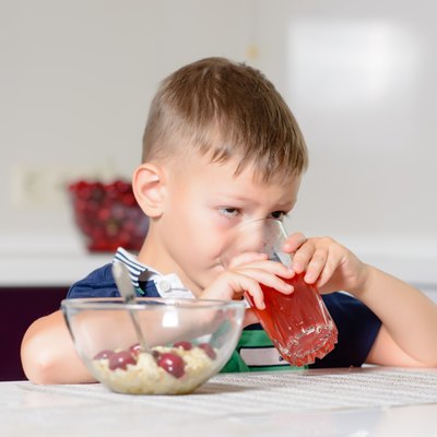 Little boy drinking fruit juice in a kitchen